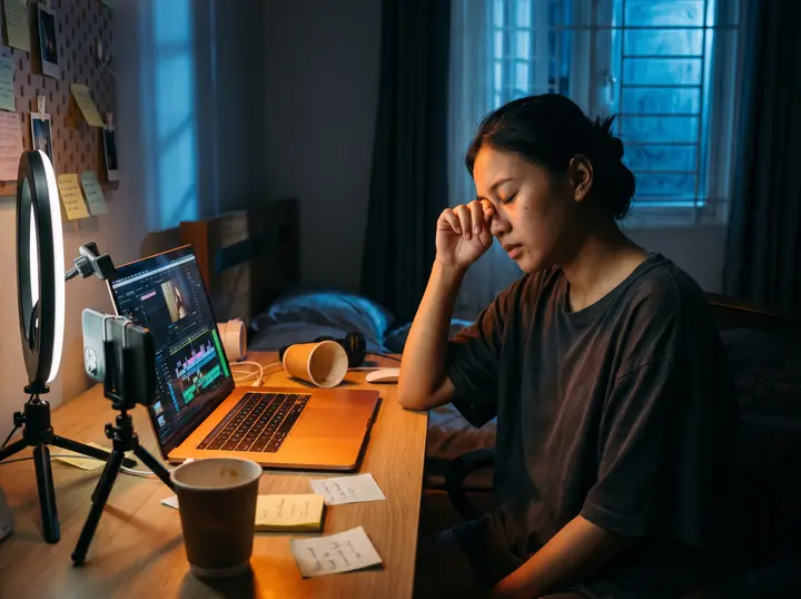 Kreator konten kelelahan mengedit video di laptop hingga larut malam